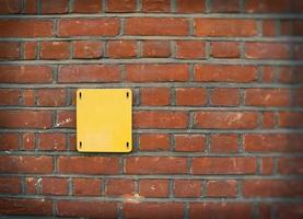 Altes leeres gelbes britisches Straßenschild auf einer roten Backsteinmauer foto