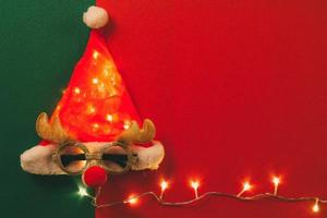 grußsaison concept.santa claus hut mit sternlicht und brille, die dekoration mit weihnachtsren auf rotem und grünem hintergrund foto