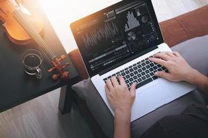 Hipster-Hand komponiert Musik mit Laptop-Computer und sitzt auf dem Sofa im Heimstudio foto