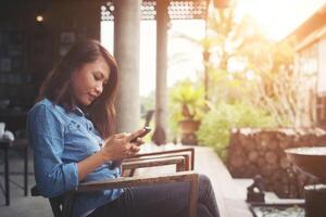 Hipster-Mädchen sitzt im Vintage-Café und benutzt Smartphone, tippt am Telefon. foto