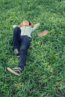 junge hipster-frau, die sich auf gras hinlegt, wenn sie müde ist, nachdem sie buch gelesen hat. foto