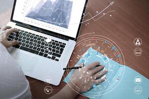 Geschäftsmannhand, die mit moderner Laptop-Computer im modernen Büro mit virtuellem Symboldiagramm arbeitet foto