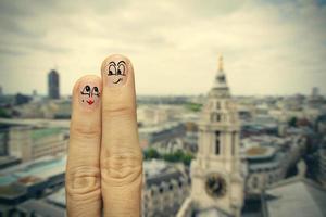 das glückliche fingerpaar, das in gemalten smiley auf londoner stadt verliebt ist, verschwommenen hintergrund foto