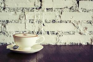 kaffeetasse espresso auf holztisch backsteinmauer hintergrund foto