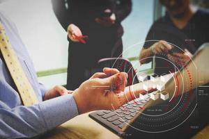 Geschäftsdokumente auf Bürotisch mit Smartphone und Laptop-Computer und Finanzdiagramm mit sozialem Netzwerkdiagramm und drei Kollegen, die Daten im Hintergrund diskutieren foto