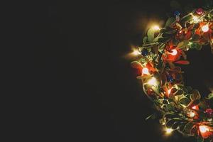 grußsaison concept.christmas kranz mit dekorativem licht auf dunklem holzhintergrund foto