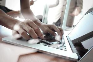 Geschäftsdokumente auf Bürotisch mit Smartphone und Laptop und zwei Kollegen diskutieren Daten im Hintergrund foto