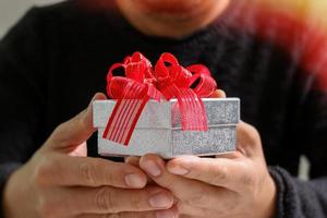 geschenk geben, man hand hält eine geschenkbox in einer geste des gebens. unscharfer hintergrund, vintage-effekt foto