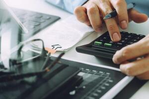 Geschäftsmann arbeitet mit Finanzen über Kosten und Taschenrechner und Laptop mit Handy auf dem Schreibtisch im modernen Büro foto