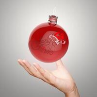 hand, die frohe weihnachten im ornamentball zeigt foto