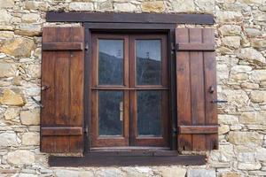 Ein altes Fenster mit Fensterläden aus Holz in einem Steinhaus. foto