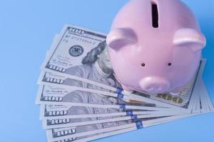 sparschwein und stapel dollarbanknoten auf blauem hintergrund, spar- und anlagekonzept foto