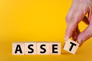 Asset - ein Wort aus Holzblöcken mit Buchstaben auf gelbem Hintergrund, ein Konzept für nützliche oder wertvolle Vermögenswerte foto
