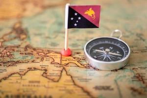 die Flagge von Papua-Neuguinea und der Kompass auf der Weltkarte. foto