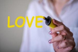 eine Frau, die das Wort Liebe mit einem gelben Marker schreibt. foto