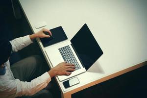 Draufsicht eines Mannes, der mit Geschäftsdokumenten auf einem Bürotisch mit einem digitalen Tablet arbeitet, und ein Mann, der mit einem intelligenten Laptop arbeitet foto