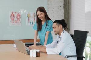 Partner des Gesundheitsteams. Zwei uniformierte junge Ärzte asiatischer Abstammung diskutieren im Büro des Krankenhauses über Medikamente. Fachpersonen sind Experten und Fachleute. foto