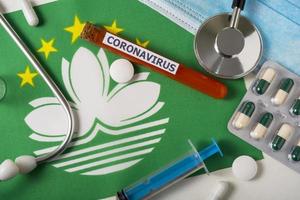 coronavirus, ncov-konzept. Draufsicht auf eine Atemschutzmaske, Stethoskop, Spritze, Pillen auf der Flagge von Macau. foto
