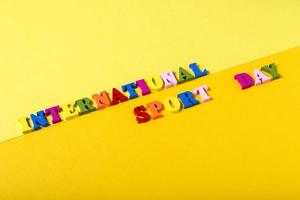 holzbuchstaben internationaler sporttag auf gelbem hintergrund. foto