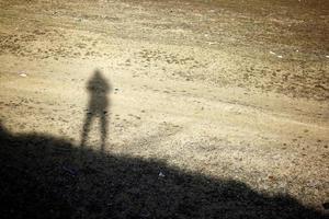 einsamer Schatten eines Mannes, der auf dem Hügel steht. menschlicher Schatten auf dem Boden. foto