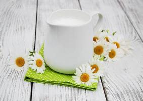 Krug mit Milch und Kamillenblüte foto