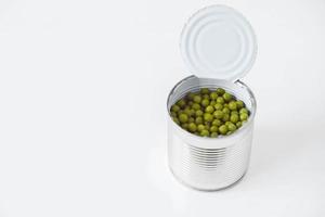 Konservierte grüne Zuckererbsen in einer offenen Aluminiummetalldose auf einem weißen Tisch. kopieren, leerer platz für text foto
