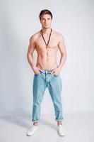 Junger muskulöser Mann mit nacktem Oberkörper in Blue Jeans auf weißem Hintergrund foto