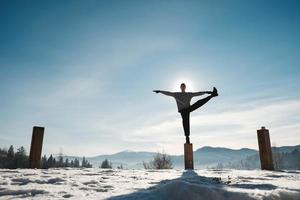 Silhouette eines Mannes, der Yoga-Übungen vor einem atemberaubenden Sonnenuntergang in den Winterbergen macht. kopieren, leerer platz für text foto