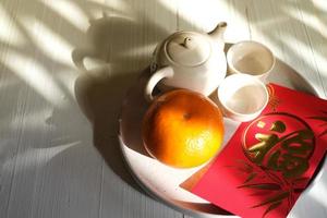 chinesisches neujahrsfestkonzept. Mandarinen, rote Umschläge, Goldbarren und Teekanne mit weißem Hintergrund. chinesisches Schriftzeichen fu, das für Glück steht foto
