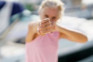 ältere frau, die draußen schattenboxen tut. Seniorin beim Sport in einem Küstenhafen foto