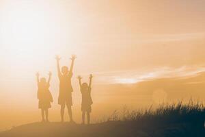 silhouette kinder, die glückliche zeit bei sonnenuntergang spielen foto