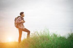 junger hipster-mann im freien mit rucksack auf der schulter, zeit zum reisen, abenteuer beim wandern. foto