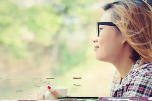 lächelnde schöne hipster-frau, die auf einer bank mit morgenkaffee sitzt. foto