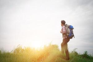 junger hipster-mann im freien mit rucksack auf der schulter, zeit zum reisen, abenteuer beim wandern. foto