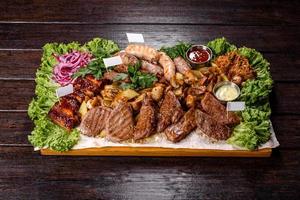 mehrere Arten von gebratenem Fleisch mit Gewürzen und Kräutern auf einem Holztablett foto