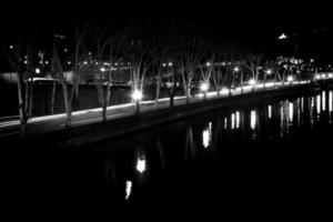 Auffahrt am Flussufer mit Nachtlichtern, die sich auf der Wasseroberfläche widerspiegeln. foto