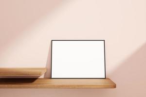 minimalistisches und sauberes horizontales schwarzes Poster oder Fotorahmen-Modell auf dem Holztisch, der an der Raumwand lehnt foto