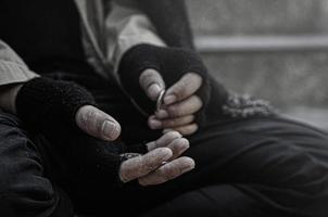 Nahaufnahme von Armen oder Obdachlosen Obdachlose bitten öffentlich um Geld. der arme Bettler in der Stadt saß mit einem silbernen Krug auf der Treppe. foto