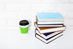 Bildungszubehör. Tasse Kaffee und Bücher auf dem Tisch in einer Klasse. draufsicht und kopierraum. selektiver Fokus