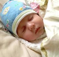 Schönes schlafendes Baby mit Kinderhut posiert Fotograf für Farbfoto foto