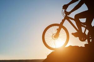 Silhouette eines Mannes auf dem Mountainbike während des Sonnenuntergangs. foto