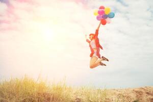 schönes Mädchen, das mit Luftballons am Strand springt foto