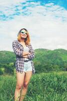 Junge schöne Hipster-Frau, die inmitten von Natur und Bergen mit verschränkten Armen steht, entspannendes Konzept foto