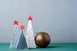 satz hölzerner weihnachtsbaum und kugeldekoration auf grauem hintergrund des grünen tisches foto