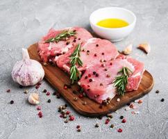 frische rohe Schweinekoteletts mit Gewürzen und Kräutern foto