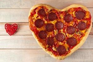herzförmige Peperoni-Pizza auf Holzhintergrund. Valentinstag Geschenk. foto
