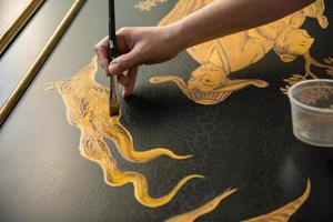 Malerdekorateur zeichnet mit einem breiten, dünnen Pinsel foto