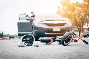 Mann, der betrunken fährt, Crash-Kinderfahrrad fährt und die Tür öffnet, um zuzusehen, indem er eine Flasche Bier hält. foto