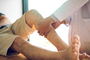 Physiotherapeuten benutzen ihre Hände, um die Waden des Patienten zu drücken, um in der Klinik auf Schmerzen und Massagen zu prüfen.
