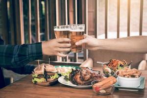 nahaufnahme jugendlicherfreunde, die mit einem glas bier toasten und klirren. foto